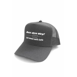 Könnte beinhalten: Dunkelgraue Trucker-Cap mit weißem Mesh-Rücken. Auf der Cap steht in weißer Schrift "Aus dem Weg!" über einer Sofa-Grafik und "ich muss aufs Sofa" darunter. Die Cap hat einen gebogenen Schirm.