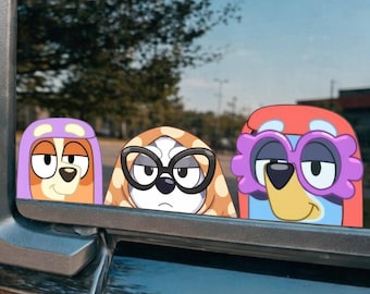 May include: A vinyl decal applied to a vehicle window featuring three cartoon dog characters. The left character wears a purple hood, the centre character has brown spots and black glasses, and the right character wears red hair and purple flower-shaped glasses.