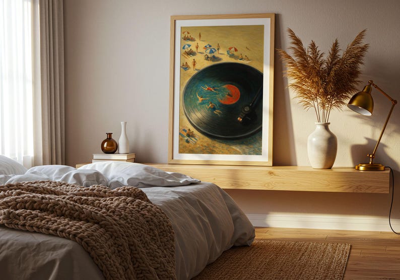 May include: Framed art print depicting a vinyl record with swimmers in the grooves, set against a beach scene. The artwork features a wooden frame and is displayed above a bed with a brown knitted blanket.