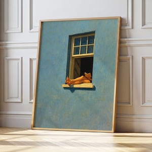 Peut inclure: Une œuvre encadrée représente un mur bleu avec une fenêtre jaune. À l'intérieur de la fenêtre, une personne lit, les jambes posées sur le rebord. L'œuvre est dans un cadre en bois clair et est appuyée contre un mur blanc.