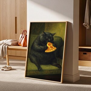 May include: Framed artwork featuring a black cat eating a slice of pizza. The cat is depicted sitting on a green sofa. The artwork has a gold frame and is displayed in a room with wooden furniture and a neutral carpet.