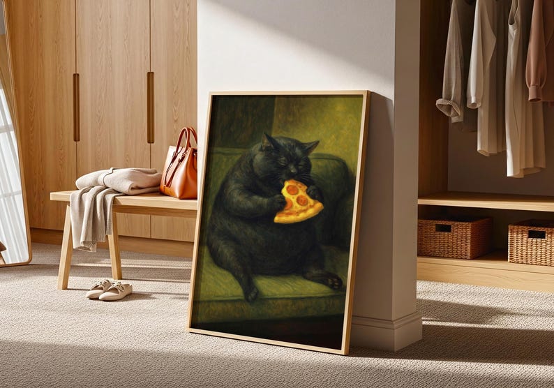 May include: Framed artwork featuring a black cat eating a slice of pizza. The cat is depicted sitting on a green sofa. The artwork has a gold frame and is displayed in a room with wooden furniture and a neutral carpet.
