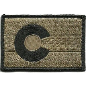 May include: A rectangular embroidered patch featuring a monochromatic tan and black colour scheme. The design displays the Colorado state flag emblem, consisting of a large black letter C surrounding a tan circle, set against a tan background.
