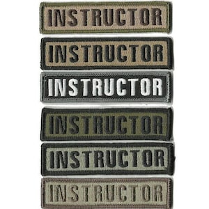 May include: A collection of six rectangular embroidered patches. Each patch features the word "INSTRUCTOR" in capital letters. The patches vary in color, including shades of green, brown, and black, with the text in contrasting colors.