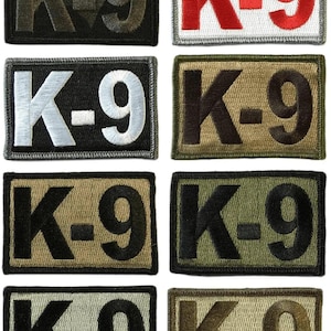 May include: Eight rectangular patches with the text "K-9" in various colors. The patches are black, white, red, and camouflage green. The text is embroidered in bold, block letters.