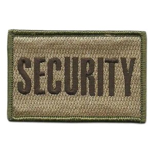 Puede incluir: Un parche rectangular con fondo verde oliva y borde bordado en marrón oscuro. La palabra SECURITY está cosida en letras mayúsculas de color marrón oscuro en el centro del parche, con un acabado de tela texturizada en toda la superficie.