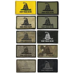 May include: A collection of rectangular patches featuring a coiled snake and the text "DON'T TREAD ON ME." The patches come in various colors, including yellow, green, and camouflage, with the snake and text in contrasting colors.