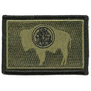 May include: A rectangular embroidered patch featuring an olive green background with a black border. The design displays a silhouette of a bison in a lighter olive green shade, with a circular black emblem centered on the bison's body.