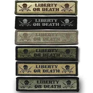 May include: A stack of six embroidered patches with the phrase "LIBERTY OR DEATH" in white capital letters. Each patch features a skull and crossbones design. The patches are in various colors, including black, olive green, and tan.