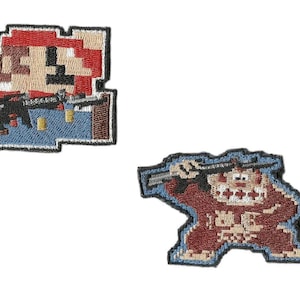 May include: Two embroidered patches featuring pixelated video game characters. One patch depicts a character in a red hat and blue overalls holding a weapon. The other patch shows a gorilla-like character with a weapon.