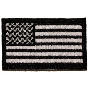 Op de afbeelding: Een rechthoekige geborduurde patch met een monochroom zwart-wit ontwerp van de vlag van de Verenigde Staten. Het kanton toont een reeks witte, stervormige stiksels op een zwarte achtergrond, met afwisselend zwarte en witte horizontale strepen.