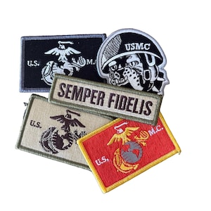 May include: A collection of five embroidered patches featuring United States Marine Corps themes. The set includes rectangular and shaped patches in black, tan, red, and white, displaying the Eagle, Globe, and Anchor emblem, a bulldog in a helmet, and the text Semper Fidelis.
