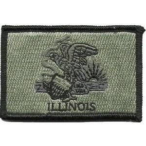 Op de afbeelding: Een rechthoekige olijfgroene geborduurde patch met een zwarte gestikte rand. Het ontwerp toont een donkergroene adelaar op een schild met een zonsopgang op de achtergrond. Het woord ILLINOIS is onderaan in donkergroene hoofdletters geborduurd.