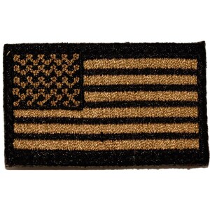 Op de afbeelding: Een rechthoekige geborduurde patch met een gestileerd ontwerp van de vlag van de Verenigde Staten. De patch is gemaakt van zwart en metallic goudkleurig garen, waarbij het goud de sterren en strepen vormt tegen een zwarte achtergrond.