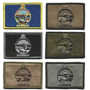 May include: A collection of rectangular patches featuring the Kansas state seal and the word "KANSAS". The patches are in various colors, including blue, black, green, and tan. The Kansas seal is a circular design with a landscape and the sun.