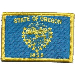 Peut inclure: Un écusson rectangulaire brodé représentant le drapeau bleu et jaune de l'État de l'Oregon. Le motif comprend le texte STATE OF OREGON en haut, l'année 1859 en bas et un emblème central entouré d'un cercle d'étoiles de couleur jaune.