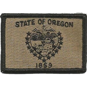 Peut inclure: Un écusson rectangulaire brodé en beige et noir portant le texte STATE OF OREGON en haut et 1859 en bas. Le centre présente un emblème détaillé du sceau de l'État de l'Oregon entouré d'un cercle d'étoiles, le tout en fil noir.