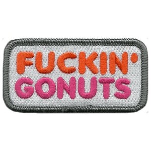 Pode incluir: Um emblema retangular bordado com fundo branco e borda cinza-escura. O texto FUCKIN' está bordado em laranja e o texto GONUTS está bordado em rosa, ambos em uma fonte negrito, arredondada e sem serifa.