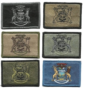 May include: Rectangular embroidered patches in various colors, including black, tan, and blue. Each patch features a detailed emblem with deer flanking a crest and the text "TUEBOR". These patches are likely for clothing or accessories.