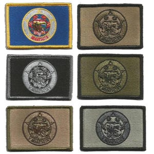 May include: A collection of embroidered patches featuring the Minnesota state seal. The patches are rectangular with various background colors, including blue, black, olive green, and tan. The state seal is circular, with detailed imagery and the word "Minnesota" below.