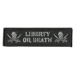 May include: A rectangular black embroidered patch featuring the text LIBERTY OR DEATH in white capital letters. On each side of the text is a white embroidered skull positioned above two crossed swords, creating a pirate-themed design.