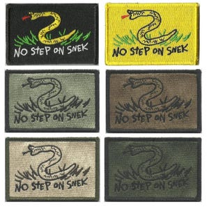May include: Rectangular embroidered patches featuring a coiled snake above the text "NO STEP ON SNEK." The patches come in various colors, including black, yellow, green, and brown. The snake is yellow or gray, with a red tongue.