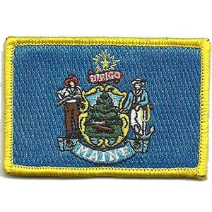 Pode incluir: Um emblema retangular bordado com o design da bandeira do estado do Maine sobre um fundo azul com uma borda amarela. O centro exibe um escudo com um pinheiro e um alce, ladeado por um agricultor e um marinheiro, com o texto MAINE abaixo.