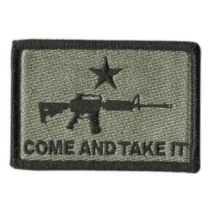 May include: A rectangular olive green embroidered patch with a black border. The design features a black silhouette of a rifle centered below a black star. The text COME AND TAKE IT is embroidered in black capital letters along the bottom edge.