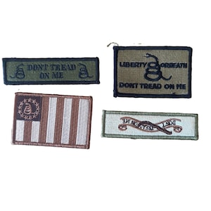 May include: Four rectangular embroidered patches featuring Gadsden flag imagery. One olive patch reads DONT TREAD ON ME. A larger olive patch reads LIBERTY OR DEATH DONT TREAD ON ME. A brown and white striped flag patch. A white patch with a ribbon design.