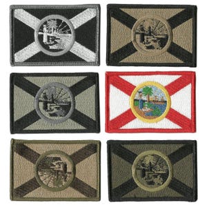 May include: Six embroidered patches featuring the Florida state flag design. Each rectangular patch has a central circular emblem with a palm tree and water scene, surrounded by a white and red or black and tan background.