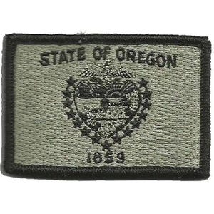Peut inclure: Un écusson rectangulaire brodé en vert olive et noir portant le texte STATE OF OREGON en haut et 1859 en bas. Le centre présente un emblème brodé détaillé du sceau de l'État de l'Oregon avec des étoiles et un paysage.