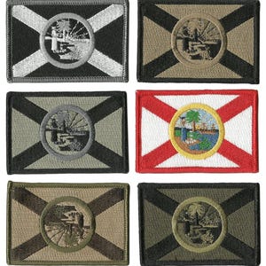May include: A collection of embroidered patches featuring the Florida state flag. Each patch has a rectangular shape with a central circular emblem. The patches display various color schemes, including black, tan, and red, with the state seal in the center.