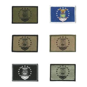 May include: A collection of six embroidered patches featuring the United States Air Force emblem. The patches are rectangular with various color schemes, including olive green, blue, tan, and black. Each patch displays the emblem, a stylized eagle, stars, and a shield.
