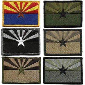 May include: A collection of six embroidered patches featuring the Arizona state flag design. The patches showcase the flag's iconic sunburst and star emblem in various color schemes, including red, yellow, blue, green, black, and tan.