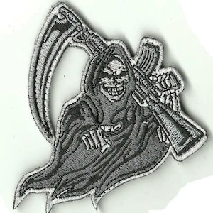 May include: Embroidered patch featuring a grim reaper figure in a hooded cloak, holding a scythe and an assault rifle. The design is in shades of gray and white, with detailed stitching. The patch has a jagged edge.