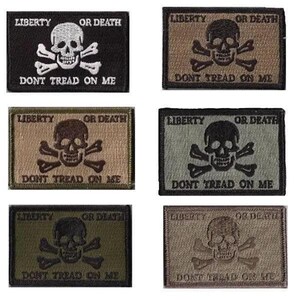 May include: A collection of six rectangular patches featuring a skull and crossbones design. Each patch has the words "LIBERTY OR DEATH" and "DONT TREAD ON ME" embroidered on them. The patches are in various colors, including black, tan, and olive green.