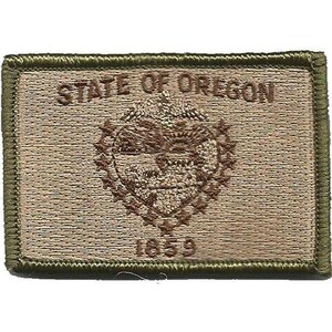 Peut inclure: Un écusson rectangulaire brodé en vert olive et beige portant le texte STATE OF OREGON en haut et 1859 en bas. Le centre présente un emblème brodé du sceau de l'État de l'Oregon entouré d'un cercle de petites étoiles.