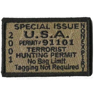 May include: A rectangular embroidered patch with a tan background and black border. The text reads: SPECIAL ISSUE U.S.A. 2001 PERMIT# 91101 TERRORIST HUNTING PERMIT No Bag Limit Tagging Not Required. The word NONEXPIRY is written vertically on the right side.