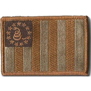 May include: A rectangular embroidered patch featuring a monochromatic brown and tan color scheme. The design displays a coiled snake surrounded by a circle of thirteen stars in the upper left corner, with alternating vertical stripes throughout.