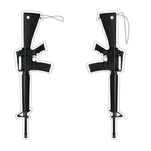 May include: Two black rifle-shaped stickers with white outlines are displayed against a white background. Each sticker features a detailed depiction of a rifle, including the barrel, magazine, and stock. A black string is attached to the top of each sticker.