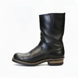 May include: Black leather boot with a rounded toe and a mid-calf shaft. The boot features a strap across the ankle and a stacked heel. The sole is brown with a light-coloured stitch.