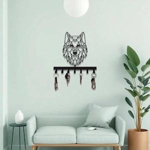 May include: A black metal key holder with a geometric wolf head design. The key holder has a horizontal bar with hooks, each holding keys. The wolf head is mounted above the key holder, creating a decorative and functional piece for the home.