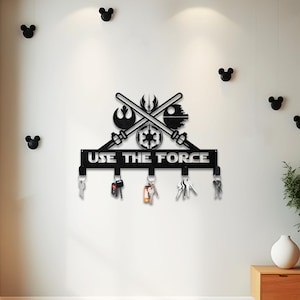 May include: Black metal key holder with the text "USE THE FORCE" and Star Wars-themed symbols. The key holder has several hooks with keys hanging from them. Decorative black Mickey Mouse head wall accents are also visible.