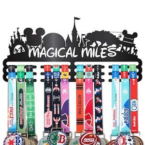 May include: Black metal medal display with the words "MAGICAL MILES" and a silhouette of a castle and Mickey Mouse ears. Colorful ribbons hang from the display, each with a medal attached. The medals have various designs and text.