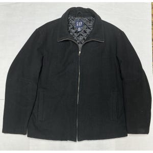 May include: Black Gap jacket with a full zip. The jacket features a collared neckline and two front pockets. The interior lining is quilted. The Gap logo is visible on the inside collar.