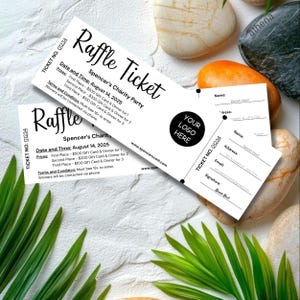 May include: Two white raffle tickets with black text, featuring the words "Raffle Ticket" and event details. One ticket is partially visible, with a space for a logo and contact information. The tickets are set against a background of decorative stones and greenery.