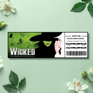 Könnte beinhalten: Ein schwarz-grünes Ticket für das Musical "Wicked" mit dem Text "ADMIT ONE" und Veranstaltungsortinformationen. Das Ticket zeigt eine Hexenillustration und den Titel der Show. Der Hintergrund ist hellgrün mit floralen Akzenten.