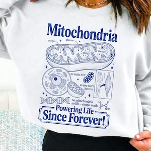 Könnte beinhalten: Weißes Sweatshirt mit blauem Grafikdesign mit dem Wort "Mitochondria" und wissenschaftlichen Illustrationen. Das Design enthält den Text "Powering Life Since Forever!"