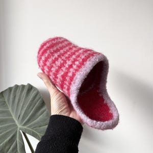 Könnte beinhalten: Ein rot-weiß gemusterter Hausschuh mit weicher, flauschiger Textur. Der Hausschuh hat eine hellrosa Einfassung und ein rotes Innenfutter. Der Hausschuh ist aus einem dicken, warmen Material gefertigt.