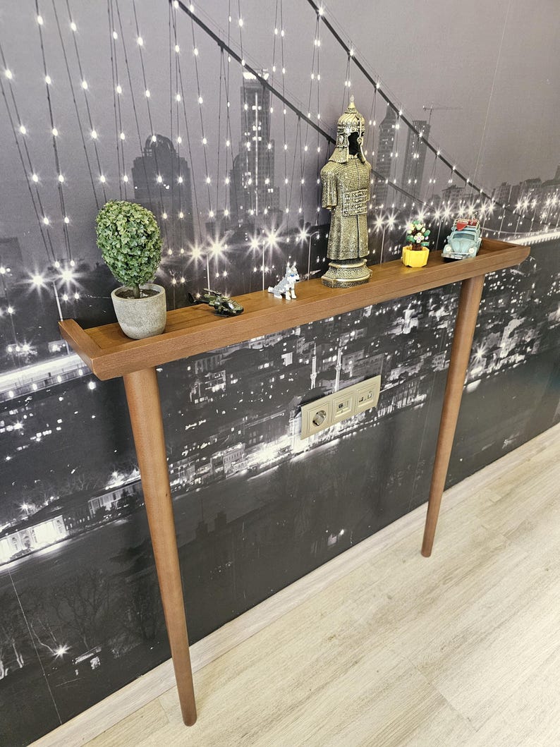 May include: A brown wooden console table with a rectangular top and four tapered legs. The table is decorated with small figurines, including a plant in a pot, a soldier statue, and a toy car. The background is a black and white cityscape.